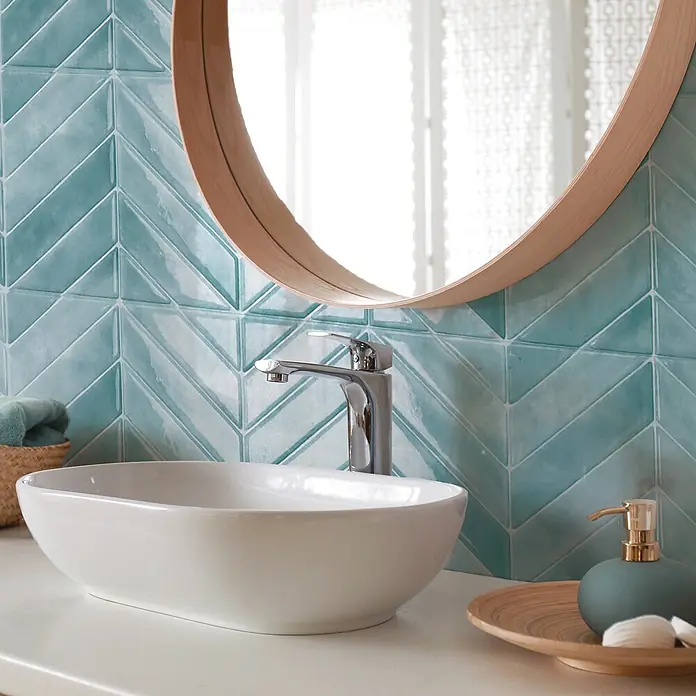 Smart Tiles Selbstklebemosaik Chevron - 29,02 x 22,86 cm, Taby, Glänzend - Ein stilvolles Badezimmer mit einem ovalen Waschbecken, einer modernen Armatur und einer grünen Seifenspendergarnitur.