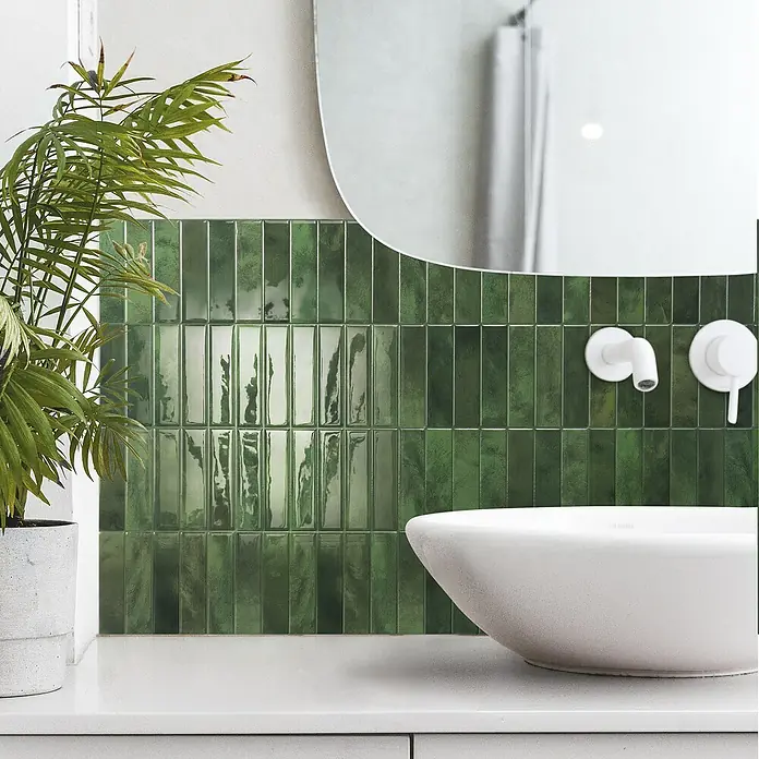 Smart Tiles Selbstklebemosaik Morocco - 29,02 x 22,86 cm, Sefrou, Glänzend - Badezimmer-Szene mit grünen, glänzenden Wandfliesen, einem weißen Aufsatzwaschbecken und Armaturen.