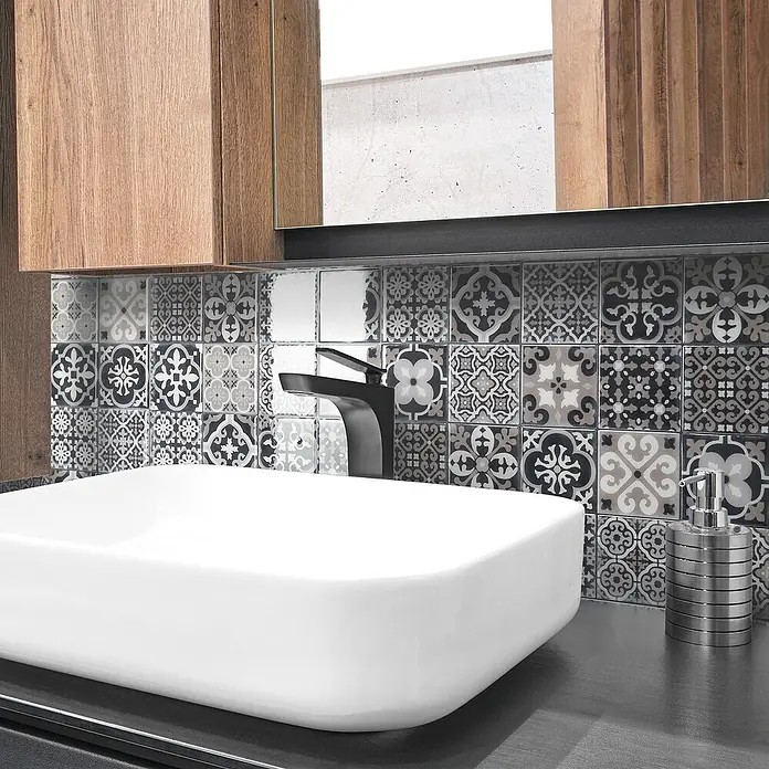 Smart Tiles Selbstklebemosaik Vintage - 22,86 x 22,86 cm, Arezzo, Glänzend - Stilvolles Badezimmer-Interieur mit einem modernen Waschbecken, dunkler Armatur und dekorativen Fliesen mit unterschiedlichen Mustern.