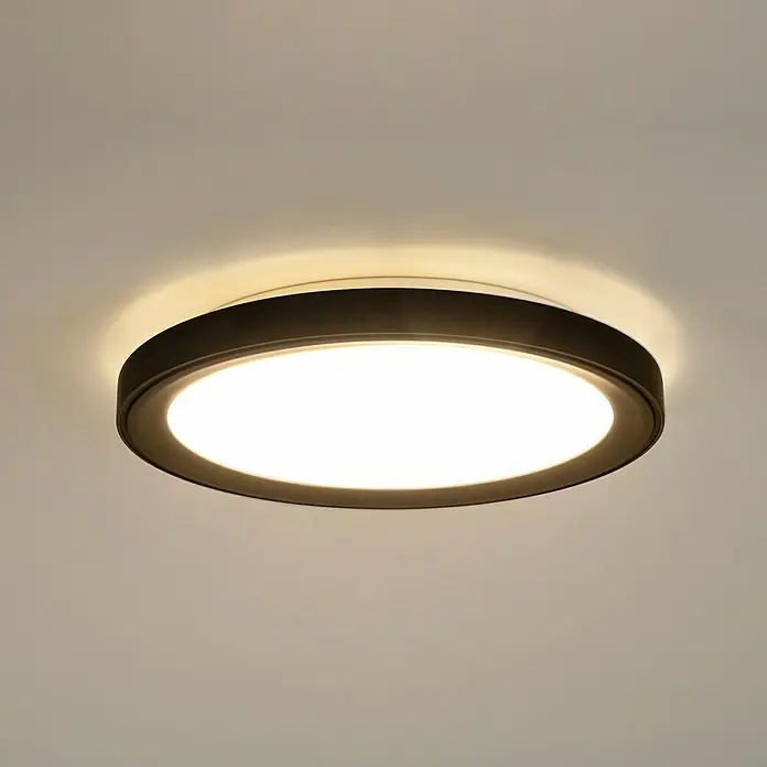 Brumberg LED-Deckenstrahler rund Anbaudownlight - Ø x H: 55 x 5 cm, Schwarz matt, Warmweiß - Nahaufnahme einer runden Deckenleuchte mit einem dunklen Rahmen, die helles Licht in einem Raum ausstrahlt.