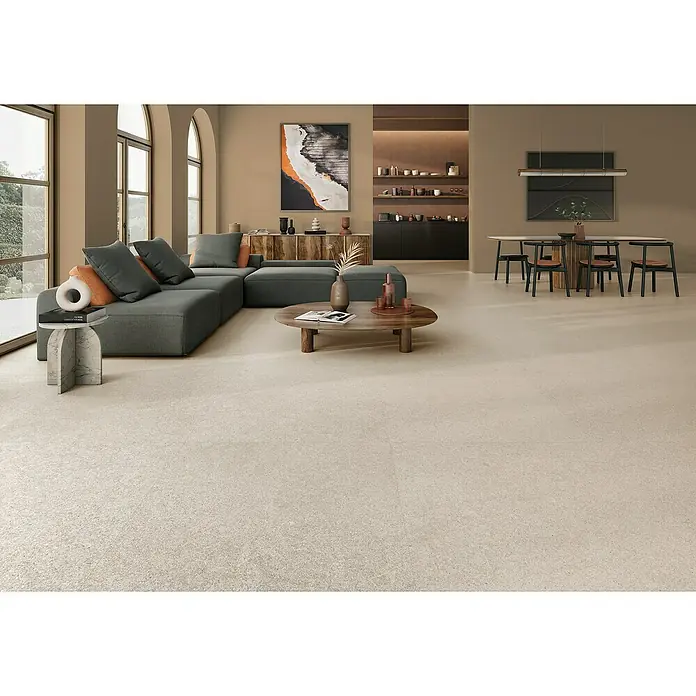 Halcón Pavimento porcelánico Everest - 60 x 60 cm, Arena, Mate, Rectificado - Elegante salón con piso de baldosas beige, sofá gris, mesa de madera y arte. El piso combina perfectamente con el interior.