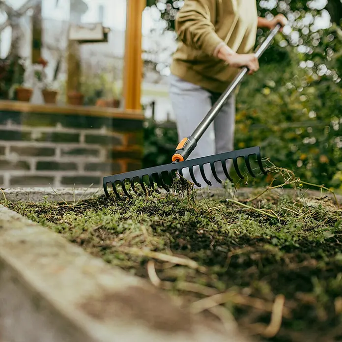 Fiskars OneClick Rasenrechen - L x B x H: 13 x 42 x 8,5 cm, 16 Stk. - Detailaufnahme eines Gardena Fächerbesens im Einsatz, perfekt zum Reinigen und Auflockern von Gartenbeeten.