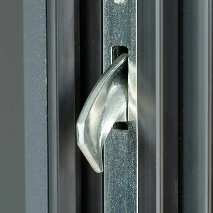 FM Türen Haustür AC68-520 RC 2 - 100 x 200 cm, DIN Anschlag: Rechts, Anthrazit - Nahaufnahme eines silbernen Türriegels an einer schwarzen Metalltür. Er ist ein Detail eines modernen Möbelstücks.