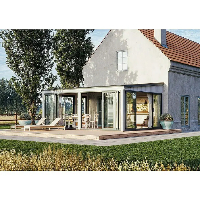 Palmako Pérgola adosada Lumi Slide Plus - L x An: 420 x 582 cm, Natural, Doble acristalamiento de 24 mm, Puerta corredera - Vista exterior de una casa con modernas puertas correderas de vidrio que se abren a una cubierta de madera, rodeada de exuberante vegetación.