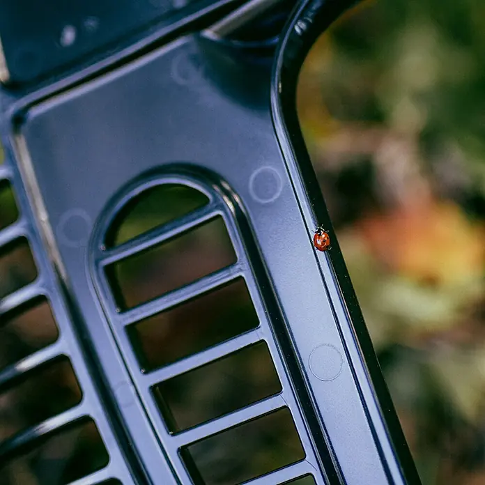 Fiskars OneClick Gartenrechen - Arbeitsbreite: 48,2 cm - Nahaufnahme eines schwarzen Kunststoffgrills mit einem Marienkäfer, der darauf sitzt. Das Design ist schlicht und modern.