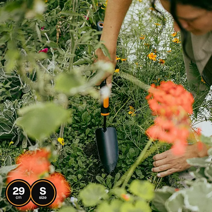 Fiskars OneClick Blumenkelle + Handgriff S - 49,1 cm - Nahaufnahme einer kleinen, schwarzen Gartenschaufel mit orangefarbenem Griff, die im Garten verwendet wird. Ideal für kleine Pflanzarbeiten.
