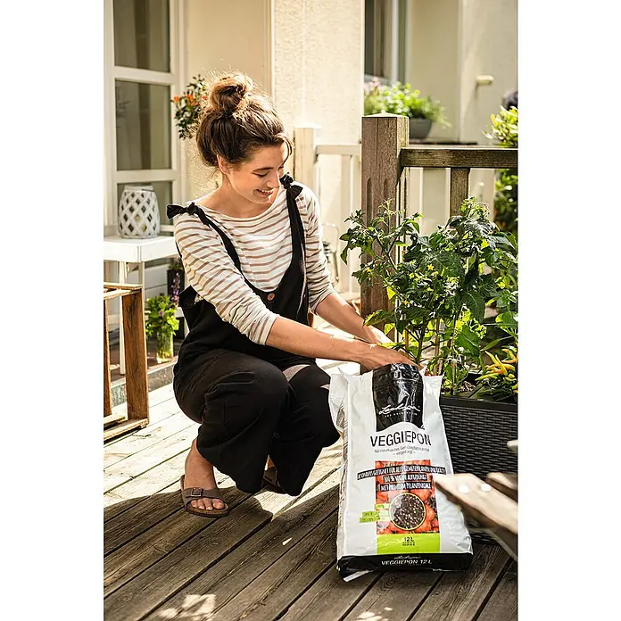 Lechuza Pflanzgranulat Veggiepon - 12 l - Frau beim Einpflanzen von Gemüse mit einem Sack Veggiepon-Pflanzerde, die für alle Gemüsepflanzen geeignet und 100% vegan ist.