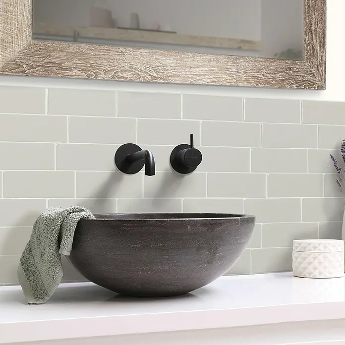 Smart Tiles Selbstklebemosaik Metro - 29,34 x 21,28 cm, Cassandra, Glänzend - Nahaufnahme einer stilvollen Waschtischarmatur mit einem modernen, runden Waschbecken und schwarzen Armaturen.
