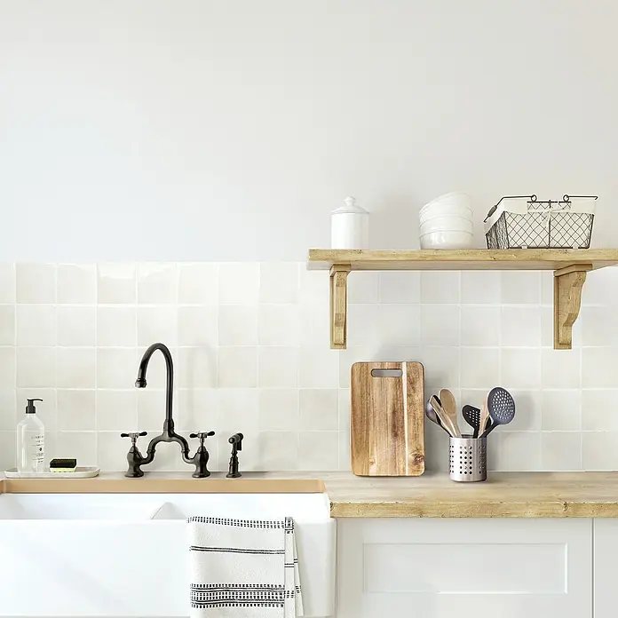 Smart Tiles Selbstklebemosaik Zellige - 22,86 x 22,86 cm, Oia, Glänzend - Küchenspüle mit Armatur, Schneidebrett, Utensilienhalter und Ablage. Die helle Küche ist modern und einladend gestaltet.