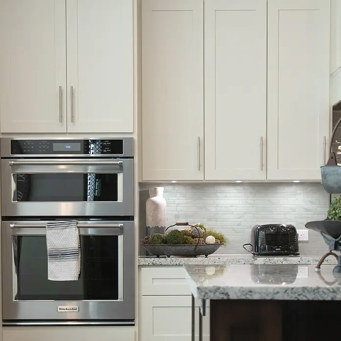 Smart Tiles Selbstklebemosaik Milano - 29,33 x 24,45 cm, Massa, Matt - Nahaufnahme eines modernen Küchenbereichs mit einem doppelten Edelstahl-Einbaubackofen von KitchenAid.