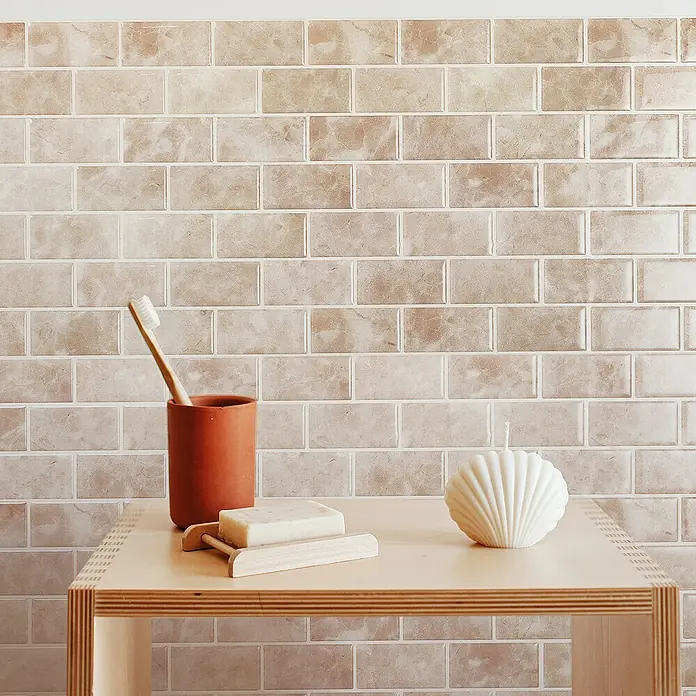 Smart Tiles Selbstklebemosaik Subway - 27,81 x 24,64 cm, Sora, Glänzend - Ein Badezimmerstillleben mit einer Seife auf einer Holzablage, einer Muschelkerze und einer Zahnbürste in einem Terrakottabecher.