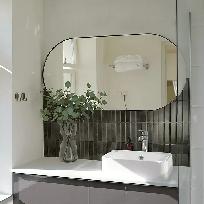 Smart Tiles Selbstklebemosaik Morocco - 29,02 x 22,86 cm, Zaida, Glänzend - Elegantes Badezimmerwaschbecken mit Armatur und ovalem Spiegel. Die dunklen Fliesen verleihen dem Raum eine stilvolle Note.