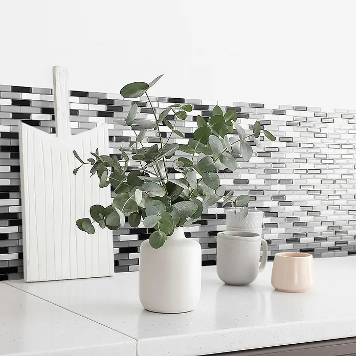 Smart Tiles Selbstklebemosaik Murano - 25,92 x 23,11 cm, Metallic, Glänzend - Nahaufnahme einer Küchendekoration mit stilvollen Wandfliesen, einer eleganten Vase und passenden Tassen.