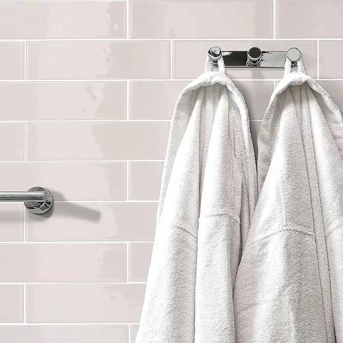 Smart Tiles Selbstklebemosaik Oslo - 57,31 x 27,62 cm, Grey, Glänzend - Wandfliesen in hellem Rosa und zwei flauschige weiße Bademäntel, die an einem verchromten Handtuchhalter hängen, verleihen dem Raum eine elegante Note.