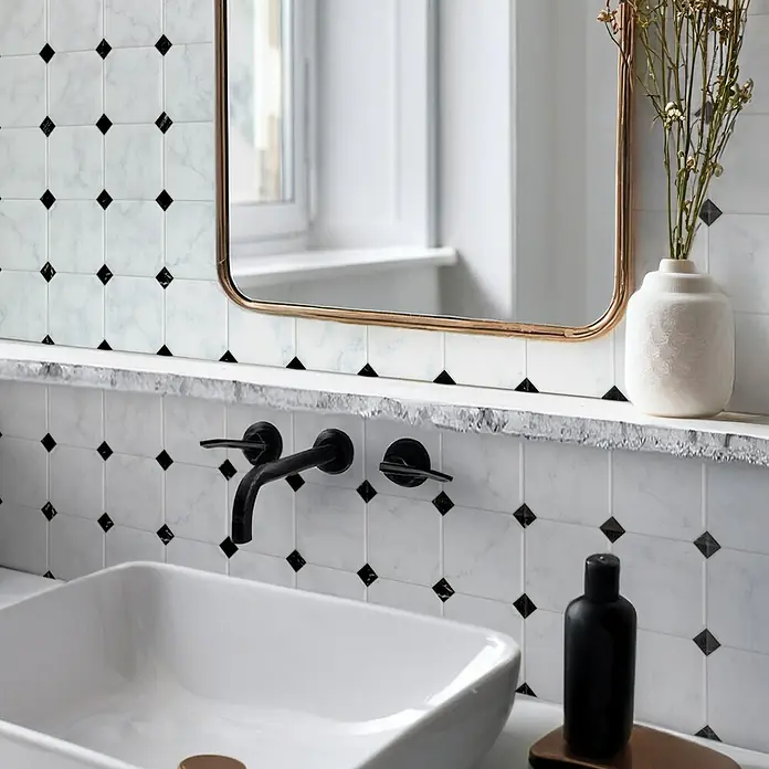 Smart Tiles Selbstklebemosaik Betera - 19,69 x 19,69 cm, Blanco, Glänzend - Badezimmer-Szene mit weißem Waschbecken, stilvoller Armatur, Marmorfliesen mit schwarzen Akzenten und einem dekorativen Spiegel.