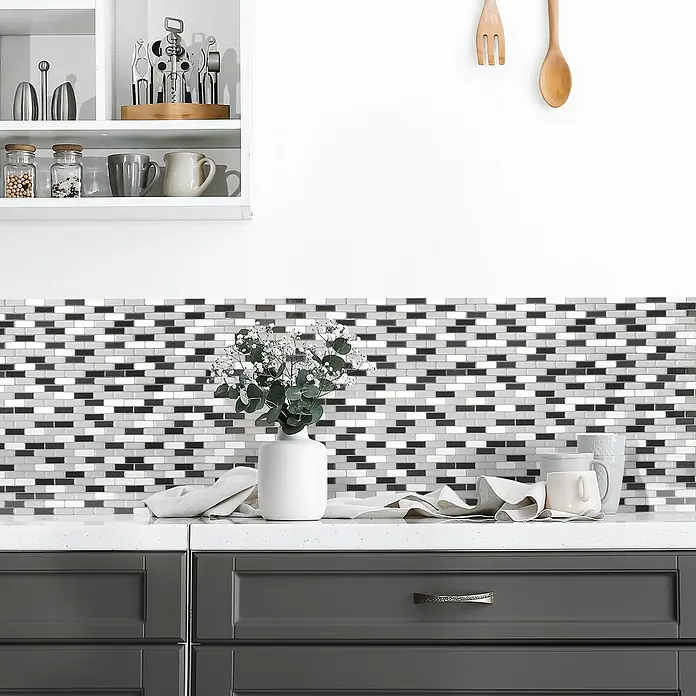 Smart Tiles Selbstklebemosaik Murano - 25,92 x 23,11 cm, Metallic, Glänzend - Küchenansicht mit stilvollen, selbstklebenden Mosaikfliesen in Grau- und Schwarztönen als Spritzschutz hinter einer modernen Arbeitsplatte.