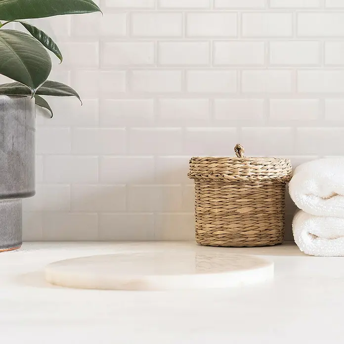 Smart Tiles Selbstklebemosaik Subway - 27,81 x 24,64 cm, White, Glänzend - Ein helles Badezimmer mit einer dekorativen Korbablage, weißen Handtüchern und einer runden Marmorplatte auf einem weißen Waschtisch.
