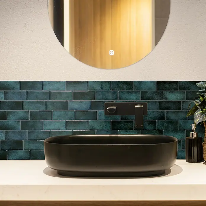 Smart Tiles Selbstklebemosaik Metro - 29,34 x 21,28 cm, Medina, Glänzend - Moderne Badezimmergestaltung mit einem eleganten, schwarzen Aufsatzwaschbecken und einer stilvollen, goldenen Spiegelbeleuchtung.