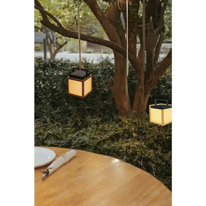 New Garden Lámpara decorativa solar Vega - Blanco cálido, Marrón, LED, IP44 - Vista atmosférica de faroles cúbicos colgando de árboles, que proporcionan un ambiente cálido para un entorno exterior acogedor.