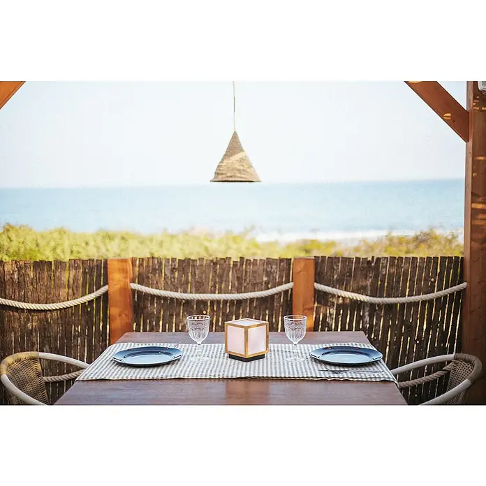 New Garden Lámpara decorativa solar Vega - Blanco cálido, Marrón, LED, IP44 - Una mesa puesta con vajilla y vasos con vistas al mar, ideal para una cena romántica.