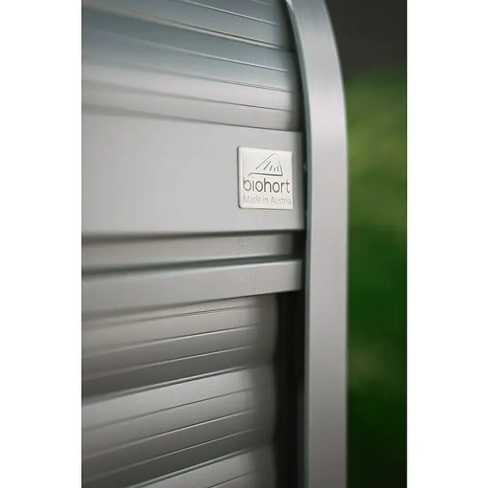 Biohort StoreMax Garten-Aufbewahrungsbox StoreMax 160 - Quarzgrau, L x B x H: 163 x 78 x 120 cm, Stahl - Detailansicht einer Biohort-Metallkonstruktion mit Rollladen und Firmenlogo, das Qualität und österreichische Herkunft verspricht.