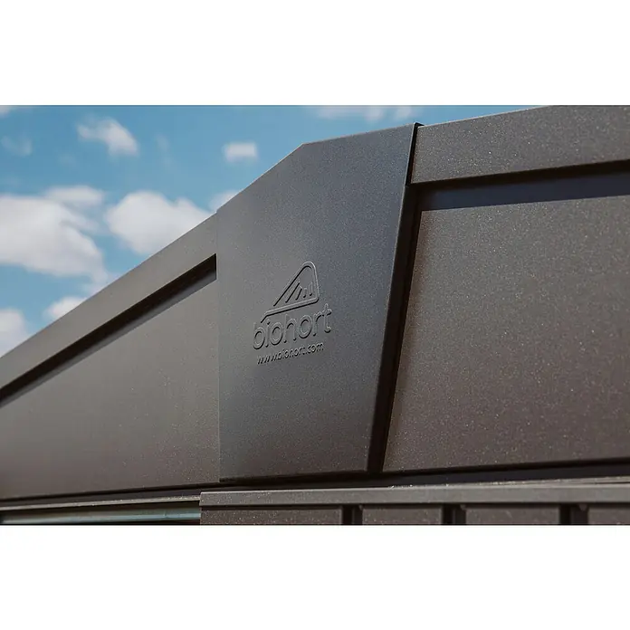 Biohort Europa Gerätehaus Gr. 7 - Außenbreite inkl. Dachüberstand: 316 cm, Außentiefe inkl. Dachüberstand: 300 cm, Stahl, Dunkelgrau Metallic - Nahaufnahme eines Biohort-Produktes mit dem Logo und der Website des Herstellers vor blauem Himmel. Das Metallprodukt ist dunkelgrau.