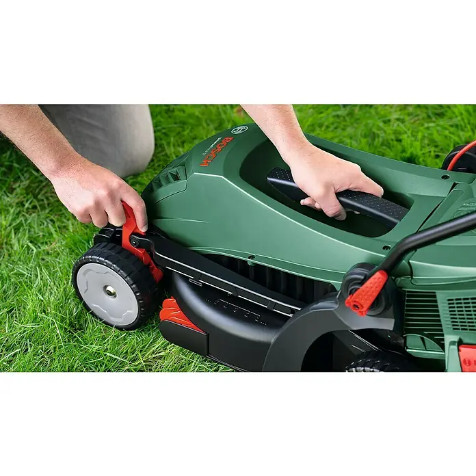 Bosch Universal Elektro-Rasenmäher UniversalRotak 37-570 - 1.400 W, Schnittbreite: 37 cm - Nahaufnahme eines Bosch Rasenmähers auf Gras, der von einer Person eingestellt wird. Der Fokus liegt auf den Verstellmechanismen.