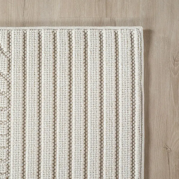 Flachgewebeteppich Helix 2201 - Creme, 110 x 60 cm, 100 % Polyester - Nahaufnahme eines beigen Teppichs mit erhabenen Streifen auf einem Holzboden, der Textur und Design des Teppichs hervorhebt.