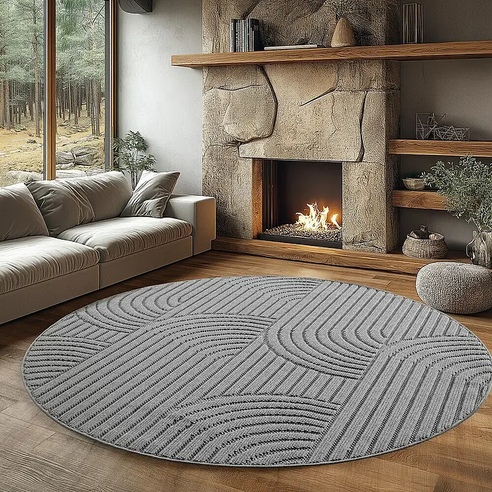 Flachgewebeteppich Helix 2201 - Silber, Durchmesser: 80 cm, 100 % Polyester - Wohnzimmer mit grauem, rundem Teppich mit geometrischem Muster vor einem Steinkamin und einem beigen Sofa.