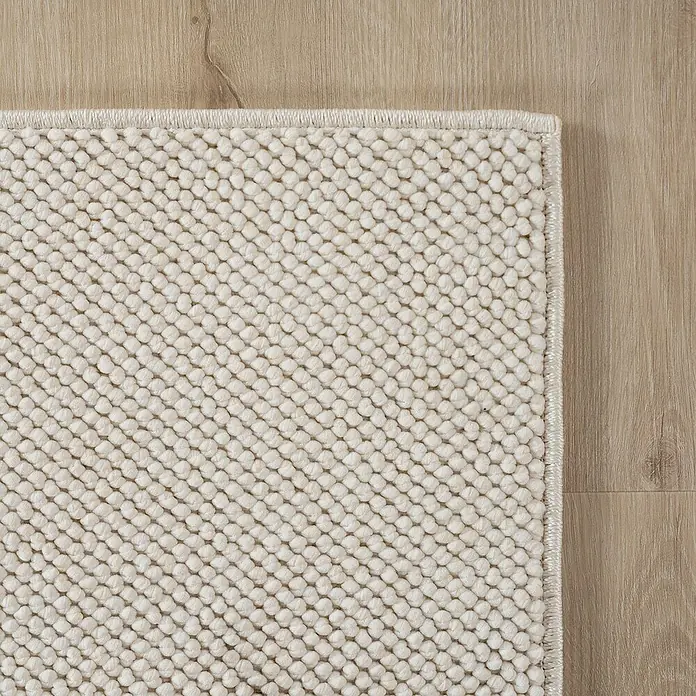 Flachgewebeteppich Helix 2200 - Creme, Durchmesser: 160 cm, 100 % Polyester - Detailaufnahme eines beigen Teppichs mit einer gewebten Textur, der auf einem hellen Holzboden liegt.