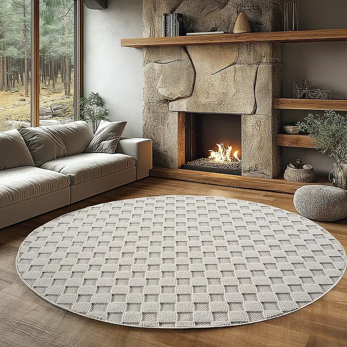 Flachgewebeteppich Helix 2203 - Creme, Durchmesser: 120 cm, 100 % Polyester - Ein hellgrauer, runder Teppich mit gewebtem Muster liegt in einem gemütlichen Wohnzimmer mit Kamin.