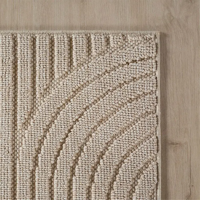 Flachgewebeteppich Helix 2201 - Beige, 370 x 280 cm, 100 % Polyester - Detailansicht eines beigen Teppichs mit modernem, linearem Muster auf einem Holzboden. Die Textur des Teppichs ist deutlich erkennbar.