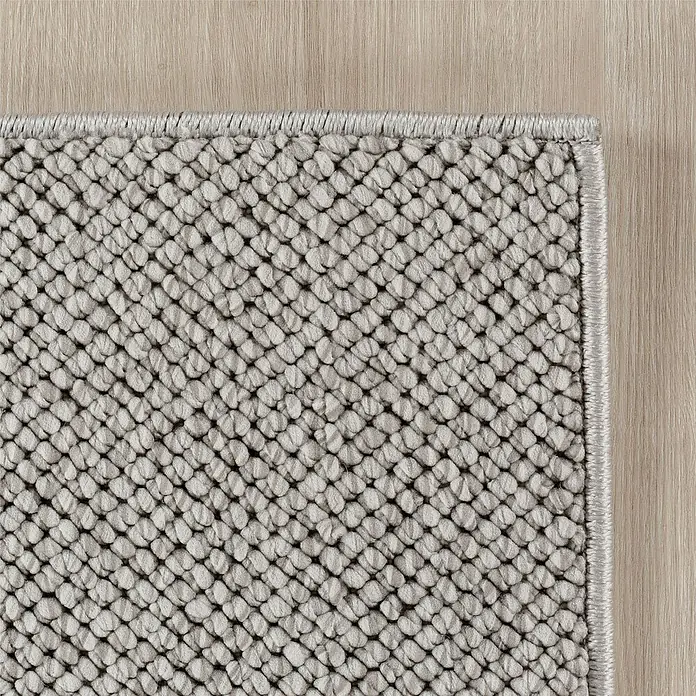 Flachgewebeteppich Helix 2200 - Silber, 170 x 120 cm, 100 % Polyester - Detailaufnahme eines grauen Teppichs mit gewebter Textur und heller Holzboden im Hintergrund. Schlicht und stilvoll für jeden Raum.