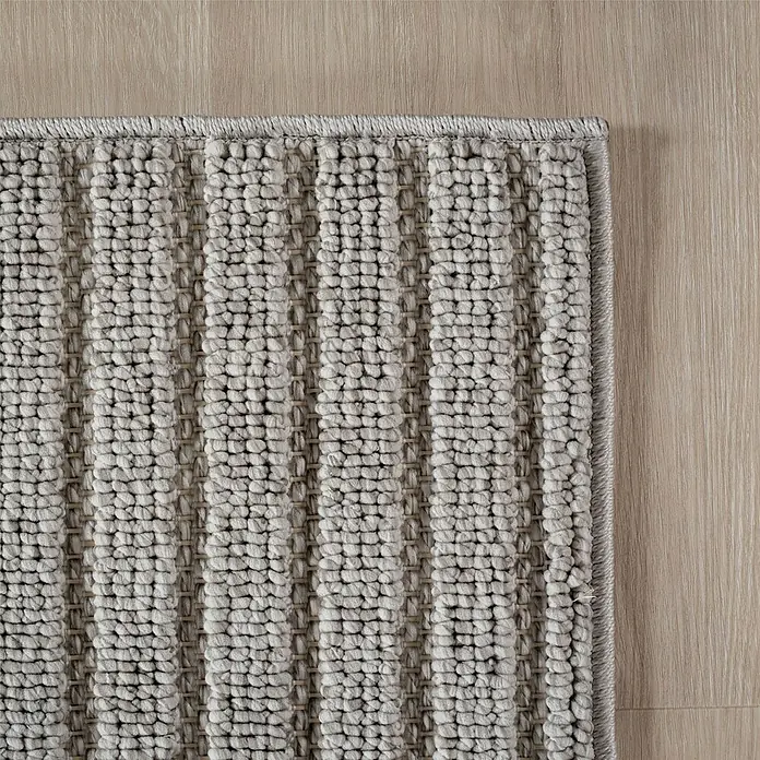 Flachgewebeteppich Helix 2201 - Silber, Durchmesser: 80 cm, 100 % Polyester - Detailaufnahme eines grauen Teppichs mit einem strukturierten, gestreiften Design auf einem hellen Holzboden.