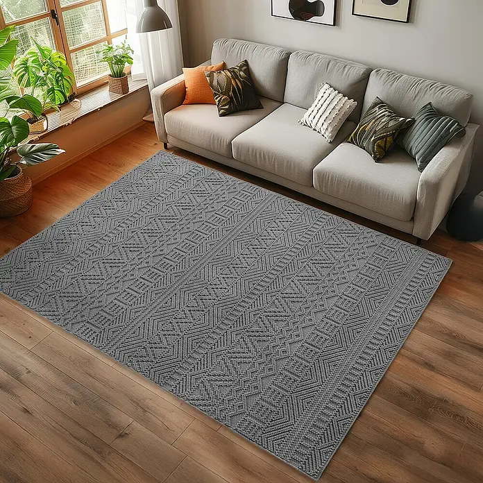Flachgewebeteppich Helix 2202 - Silber, 200 x 140 cm, 100 % Polyester - Ein grauer Teppich mit geometrischem Muster liegt vor einem Sofa in einem Wohnzimmer und verleiht dem Raum eine moderne Note.