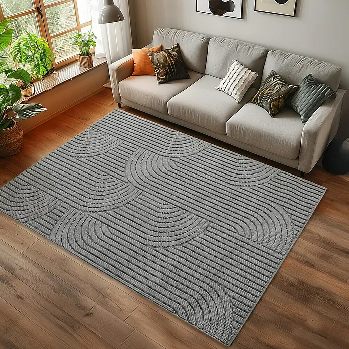 Flachgewebeteppich Helix 2201 - Silber, 290 x 200 cm, 100 % Polyester - Grauer Teppich mit abstraktem, geometrischem Muster vor einem Sofa, der dem Raum einen modernen Touch verleiht.