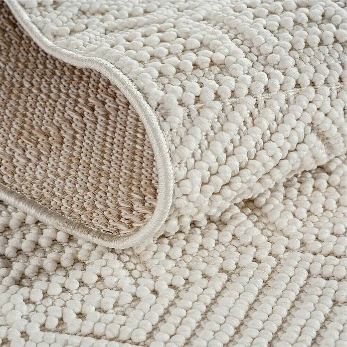 Flachgewebeteppich Helix 2202 - Creme, 250 x 80 cm, 100 % Polyester - Detailaufnahme eines beigefarbenen Teppichs mit Noppenstruktur und umgeschlagener Ecke, die die Unterseite zeigt.