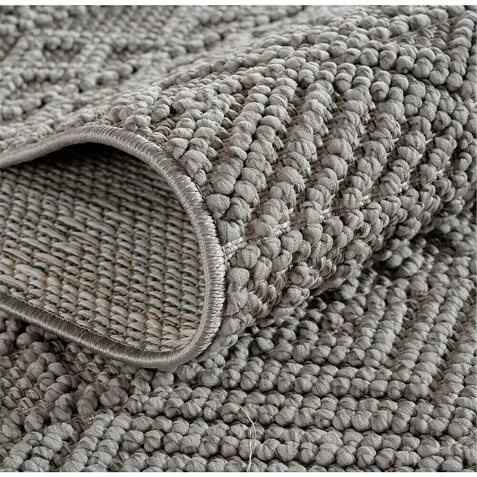 Flachgewebeteppich Helix 2202 - Silber, Durchmesser: 120 cm, 100 % Polyester - Nahaufnahme eines strukturierten grauen Teppichs mit gewebter Unterseite, der die Textur und die Details des Teppichs hervorhebt.
