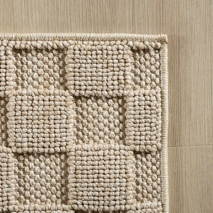 Flachgewebeteppich Helix 2203 - Beige, 340 x 240 cm, 100 % Polyester - Nahaufnahme eines beigen Teppichs mit erhabenem geometrischen Muster, der Textur und Handwerkskunst hervorhebt.