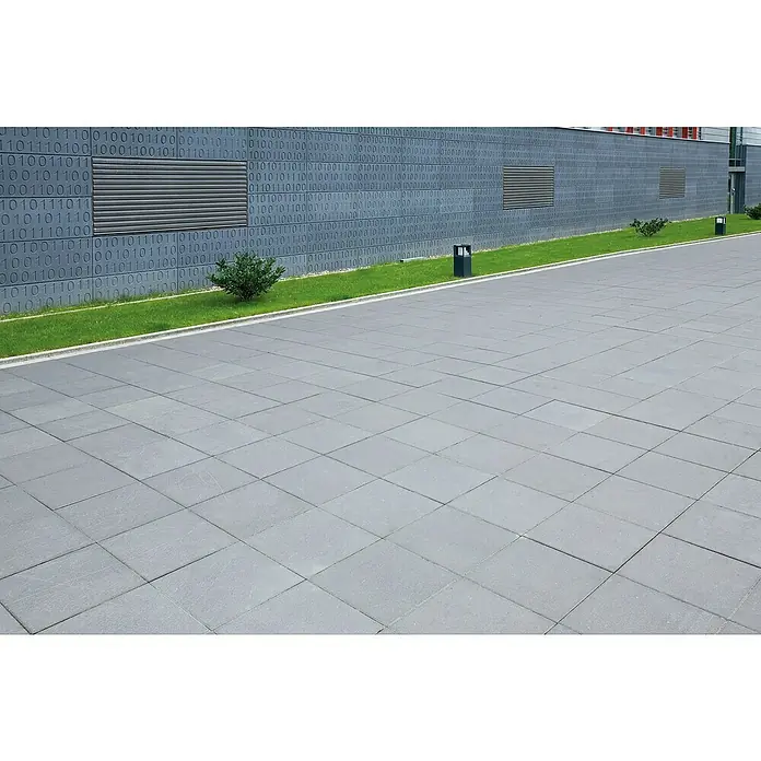 EHL Gehwegplatte - 40 x 40 x 4 cm, Grau, Beton - Eine gepflasterte Fläche mit grauen quadratischen Steinen, die einen modernen Außenbereich mit einem Gebäude im Hintergrund bildet.