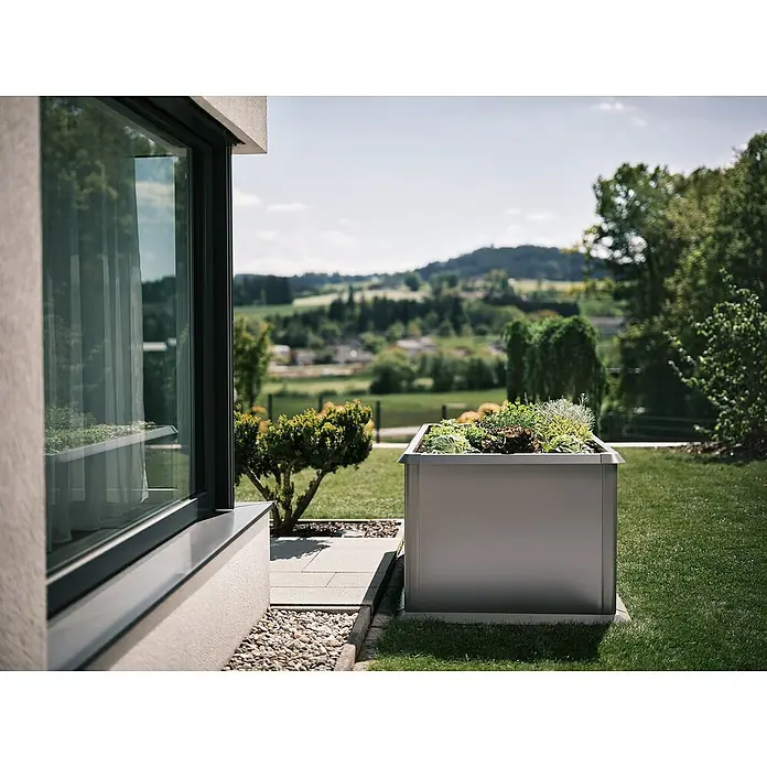 Biohort Hochbeet - 102 x 201 x 77 cm, Stahl, Quarzgrau Metallic - Nahaufnahme eines eckigen, silbernen Pflanzgefäßes mit üppiger Bepflanzung im Garten vor einem modernen Haus.