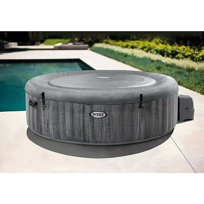 Intex Pure Spa Hidromasaje móvil Greenwood - Ø x Al: 216 x 71 cm, Gris/Blanco, 1.098 l - Primer plano de una bañera de hidromasaje Intex gris con una tapa junto a una piscina.