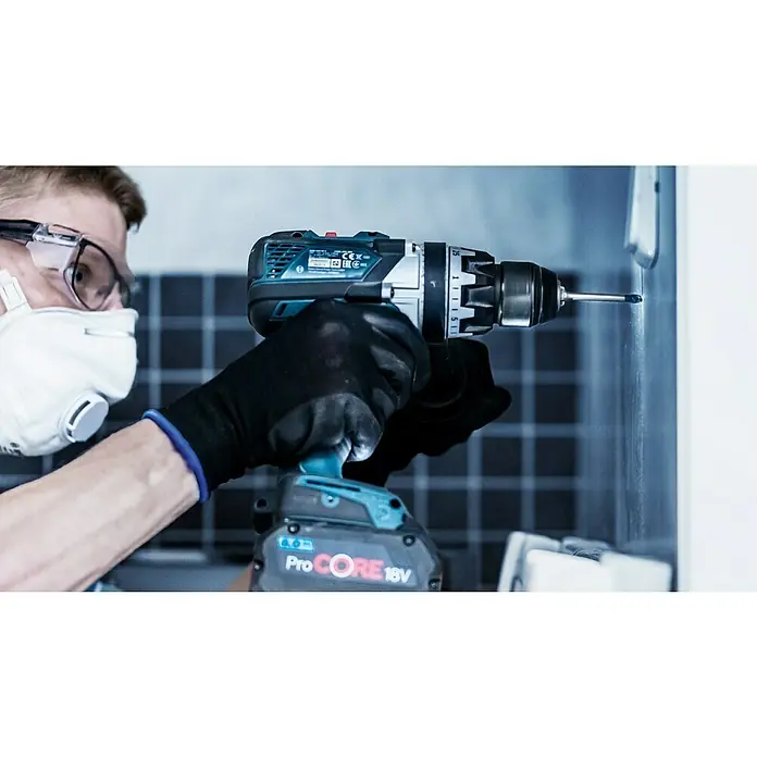 Bosch Professional Fliesenbohrer HEX-9 Hard Ceramic - Durchmesser Bohrer: 5,5 mm, Länge: 90 mm - Nahaufnahme eines Mannes mit Schutzbrille und Maske, der mit einem Akku-Bohrschrauber ProCORE 18V in eine Wand bohrt.