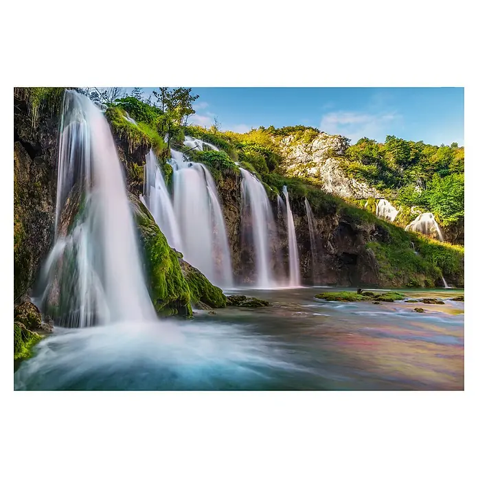 Komar Fototapete Downfall - 4 -tlg., B x H: 368 x 248 cm, Vlies - Langzeitaufnahme mehrerer Wasserfälle, die über bemooste Felsen in einen Fluss mit farbigen Spiegelungen unter blauem Himmel stürzen.