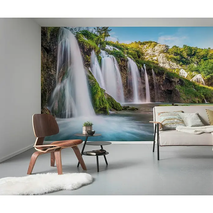 Komar Fototapete Downfall - 4 -tlg., B x H: 368 x 248 cm, Vlies - Ein Wohnzimmer mit einem stilvollen Holzstuhl, einem Beistelltisch und einem Sofa vor einer beeindruckenden Wasserfall-Fototapete.