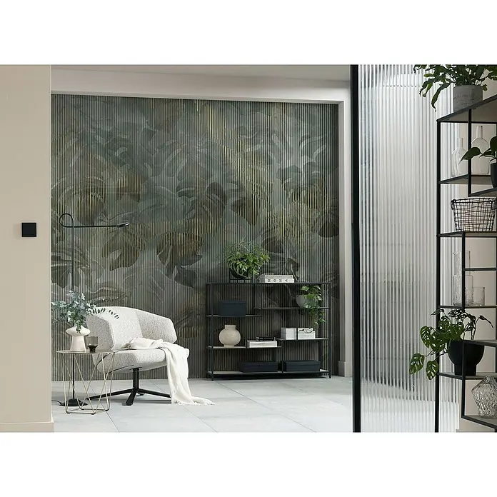 Komar Fototapete Monstera Gold - 6 -tlg., B x H: 300 x 250 cm, Vlies - Innenaufnahme eines Wohnzimmers mit einem dekorierten Regal, einem Sessel, einer Stehlampe und einer Wand mit Blättertapete.