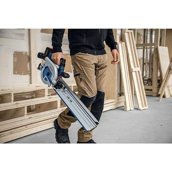 Bosch Professional AMPShare 18V Akku-Handkreissäge Pro Heavy Duty GKS 18V-57-2 GX - 18 V, Ohne Akku, Durchmesser Sägeblatt: 165 mm, 5.000 U/min - Ein Handwerker trägt eine Bosch Akku-Tauchsäge mit Führungsschiene. Perfekt für präzise Schnitte in Holz und anderen Materialien.