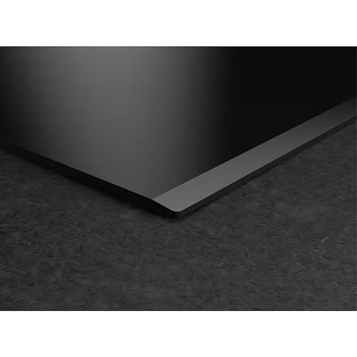 AEG Placa de cocción TO63IQ00FB - Número de fogones de inducción: 3 ud., Vidrio - Primer plano de una placa de cocina negra sobre una encimera oscura, destacando el diseño y la estética moderna del producto.