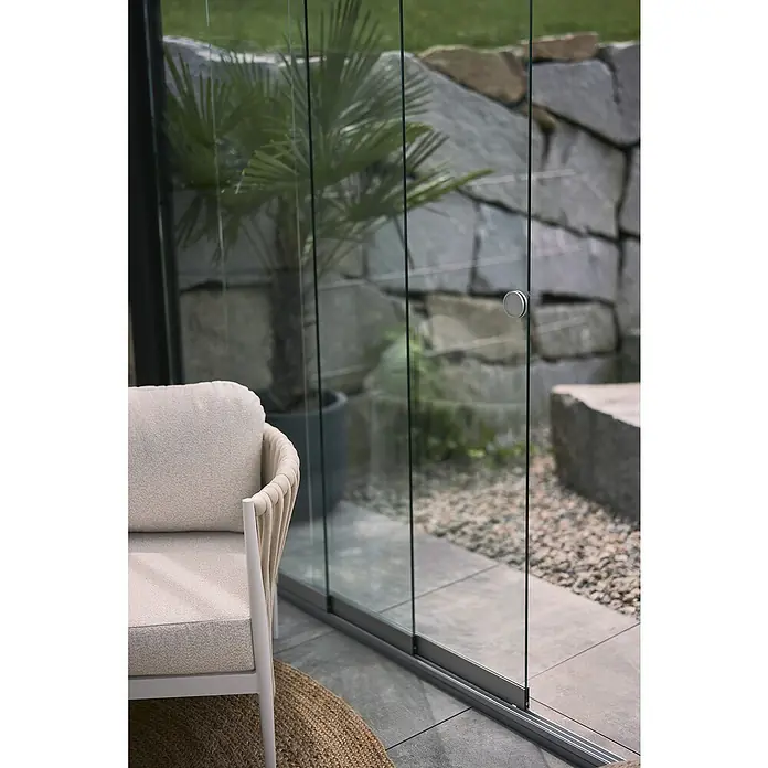 Biohort Pergola Schiebewand aus Glas - Passend für Biohort Pergola Lamellenpavillon Gr. 4, Weiß - Outdoor-Sessel mit beigefarbenen Polstern neben einem modernen Glas-Schiebetürsystem.