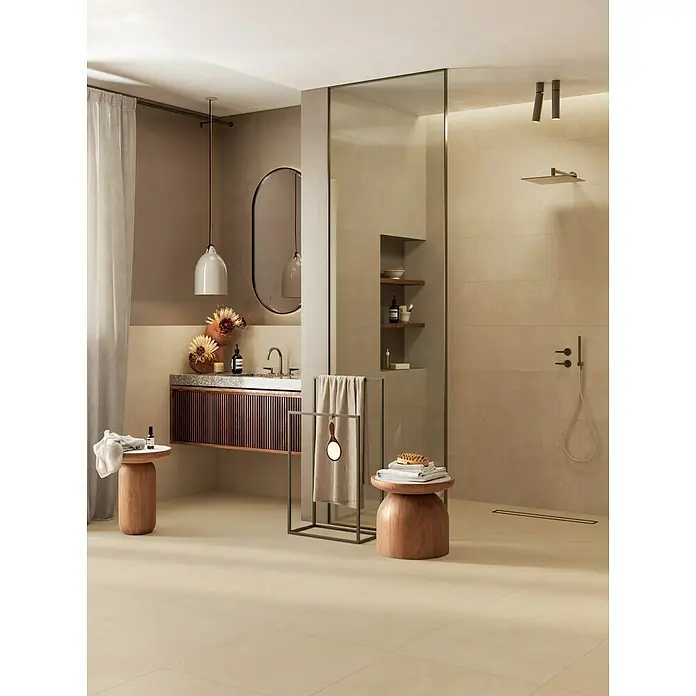 Atlas Concorde Solution Feinsteinzeugfliese Lexington - 60 x 60 cm, Gold, Matt - Modernes Badezimmer mit warmen beigefarbenen Fliesen, Holzwaschtisch und Glasduschkabine.